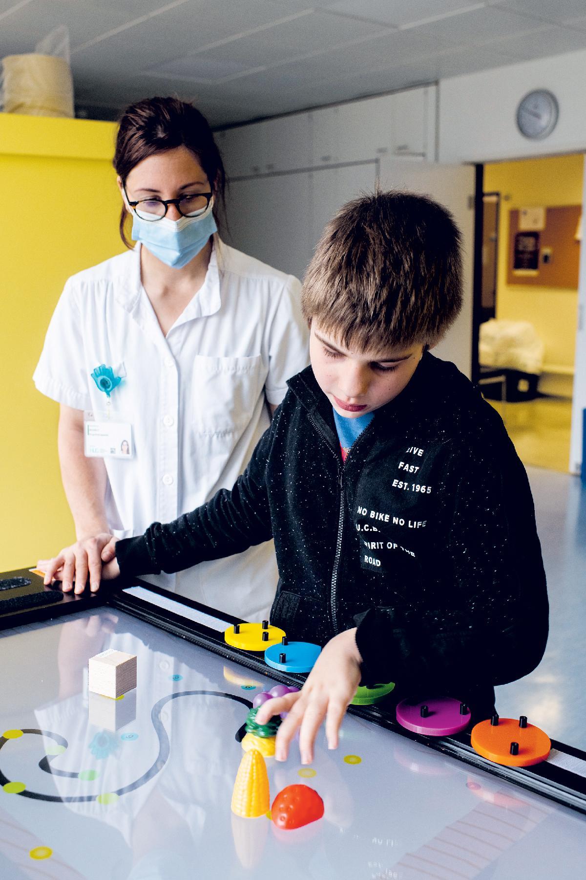 Un enfant joue avec l'écran tactile accompagné par une pédiatre